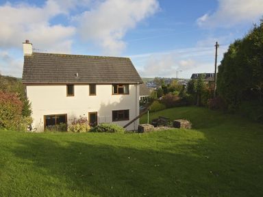 A house with windows and a sloped roof surrounded by grass and bushes in Amberley Dartmouth