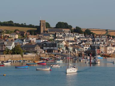 A harbor with boats docked and houses in the background under a clear sky at Bow Cottage in East Portlemouth