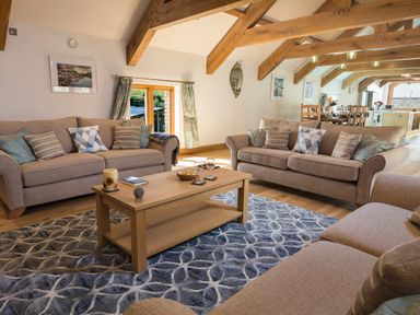 A living room with sofas and a wooden coffee table with glasses and candles at Butterwell Barn in Dartmouth