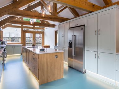 A kitchen with wooden beams a central island a stainless steel refrigerator and cabinets at Butterwell Barn Dartmouth