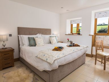 A bedroom with a bed with trays of breakfast on at Butterwell Barn in Dartmouth