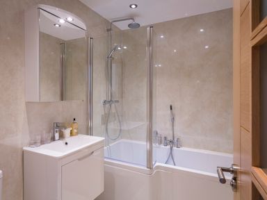 A bathroom with a bathtub shower combination sink with faucet and mirror cabinet at Butterwell Barn in Dartmouth
