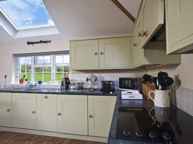 A kitchen with cabinets a stove microwave toaster kettle and window at Cloverwell in Woodleigh