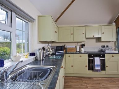 A kitchen with green cabinets a stainless steel sink and stove at Cloverwell in Woodleigh