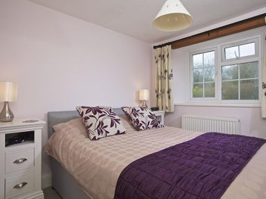 A bedroom with a double bed two bedside tables lamps and a window at Cloverwell in Woodleigh