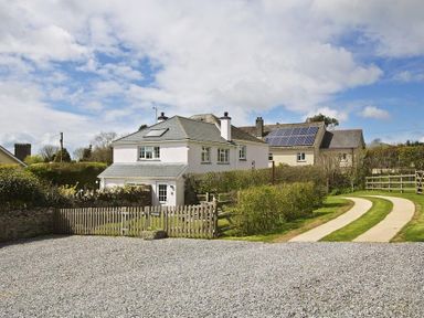 A two story house with a fenced garden and a gravel driveway with a curved grass path at Cloverwell in Woodleigh