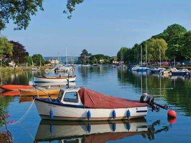 A river scene with various moored boats and trees lining the banks at Cloverwell in Woodleigh