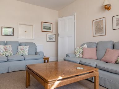 A living room with two blue sofas wooden coffee table and framed pictures on walls at Cottage View in Hope Cove