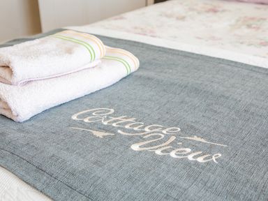 Two folded white towels placed on a bed runner with the text Cottage View in a bedroom at Cottage View in Hope Cove