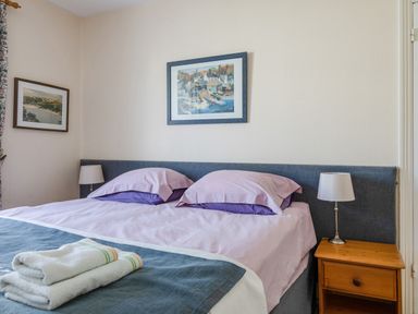 A bedroom with a double bed two bedside lamps wooden nightstand and framed pictures on the walls at Cottage View in Hope Cove