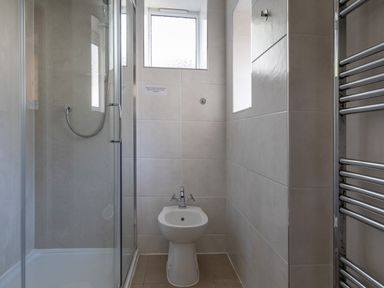 A bathroom with a shower enclosure bidet and chrome towel radiator at Cottage View in Hope Cove