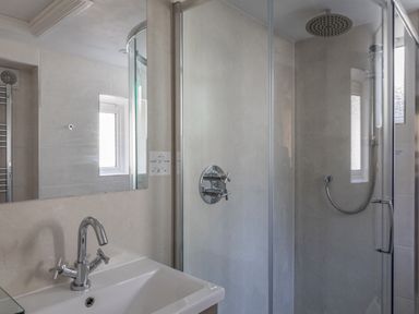 A bathroom with a sink and faucet next to a glass enclosed shower at Cottage View in Hope Cove