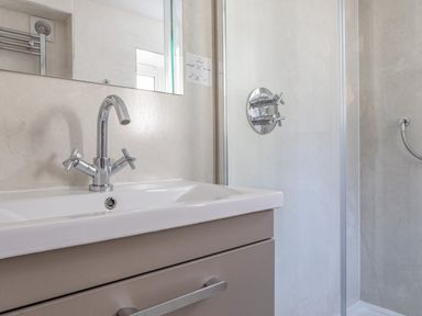 A bathroom sink with chrome faucet and a shower area with controls at Cottage View in Hope Cove