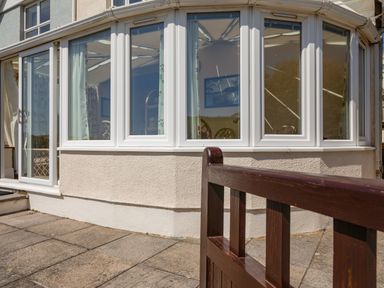 Exterior view of a building with large windows and a brown wooden gate at Cottage View in Hope Cove
