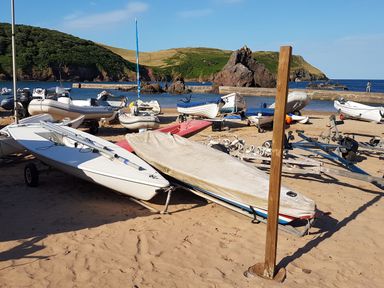 A sandy beach with small boats and trailers near the water at Cottage View in Hope Cove