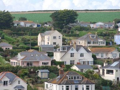 A hillside neighborhood with multiple detached houses surrounded by bushes and greenery at Cottage View in Hope Cove