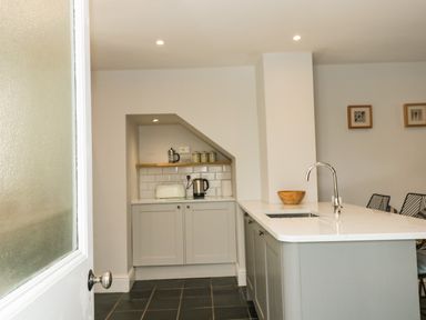 A kitchen with a white countertop island sink kettle toaster and wooden bowl at Cindys Retreat in Hope Cove
