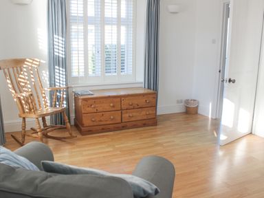 A room with a wooden rocking chair a wooden chest of drawers and a gray chair at Cindys Retreat in Hope Cove