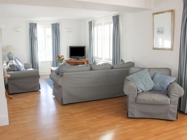 A living room with sofas and a television on a stand at Cindy's Retreat in Hope Cove