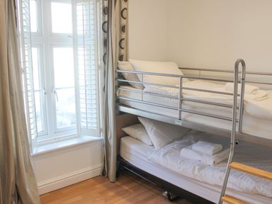 A bedroom with a metal bunk bed and a window with shutters at Cindys Retreat in Hope Cove