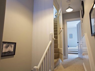 A hallway with carpeted stairs and an open door leading to a bedroom at Crab Cottage in Salcombe