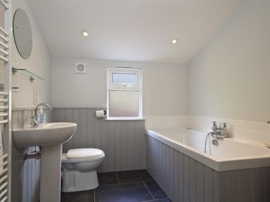 A bathroom with a sink toilet bathtub and frosted window at Crab Cottage in Salcombe