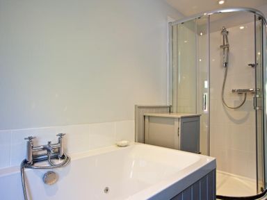 A bathroom with a bathtub and a shower enclosure with a glass door at Crab Cottage in Salcombe