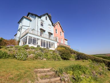 A blue and pink house on a hill with garden and stone steps at Edinburgh House in Salcombe