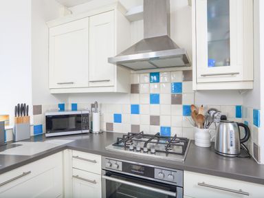 A kitchen with a gas stove oven microwave kettle and utensils at Edinburgh House in Salcombe