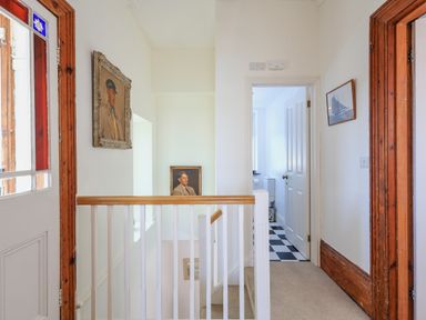 A hallway with a staircase and framed portraits on the walls at Edinburgh House in Salcombe