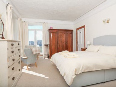 A bedroom with a double bed two armchairs a wooden wardrobe and a white chest of drawers at Edinburgh House in Salcombe