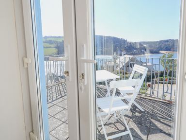 A balcony with white chairs and table overlooking a coastal landscape at Edinburgh House in Salcombe