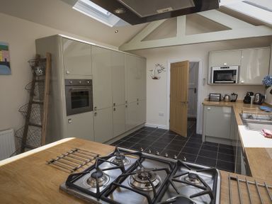 A kitchen with a gas stove on a wooden countertop cabinets oven microwave and a wooden door at Gooder House in Dartmouth