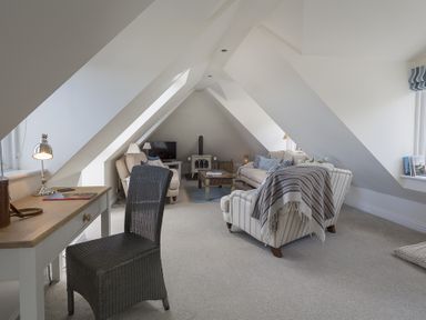 An attic living room with a desk and chair and sofas around a coffee table at Gooder House in Dartmouth
