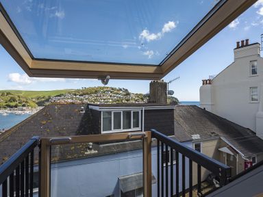 A view from a balcony showing rooftops hills sea and boats at Gooder House in Dartmouth