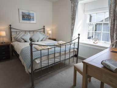 A bedroom with a metal bed frame bedside tables and lamps a wooden desk and window at Gooder House in Dartmouth