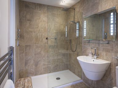 A bathroom with a walk in shower glass shower screen floating sink mirror and towel rack at Gooder House in Dartmouth