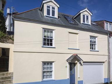 A two story cream house with blue window trims and door and garage at Gooder House in Dartmouth