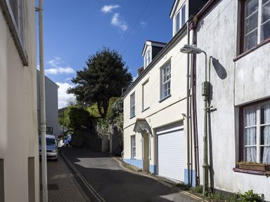 A narrow street with parked vehicles and houses with windows and a garage door at Gooder House in Dartmouth