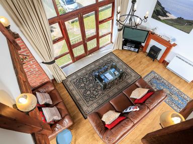 A living room with two leather sofas a glass coffee table and a television at The Granary Malborough