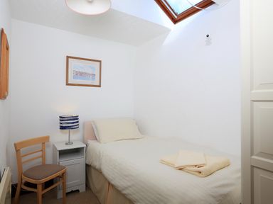 A small bedroom with a single bed a chair a nightstand with a lamp and a skylight at The Granary Malborough