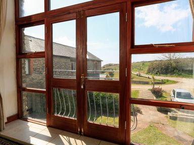 A window with wooden frames overlooking a stone building and a car parked outside at The Granary Malborough