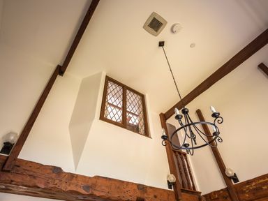 A ceiling with wooden beams a hanging chandelier and a window with lattice at The Granary Malborough