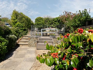 A garden with stone steps leading to a patio with a table and chairs and a bench at The Granary Malborough