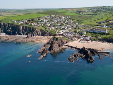 A coastal village with houses near cliffs and a sandy beach at The Granary Malborough