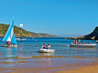A beach with boats and people on the water at Hazel Cottage in Malborough