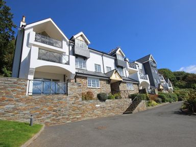 A multi-story residential building with balconies and stone lower walls at The Hoot 16 St Elmo Court in Salcombe