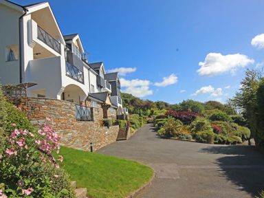 A driveway next to a multi story building with balconies and landscaped garden at The Hoot 16 St Elmo Court in Salcombe