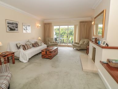 A living room with a sofa and armchairs a wooden coffee table and a fireplace at The Hoot 16 St Elmo Court in Salcombe