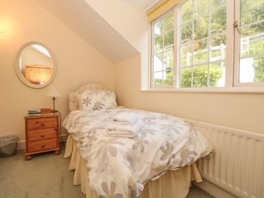 A bedroom with a single bed next to a window and a bedside table with a lamp at The Hoot 16 St Elmo Court Salcombe